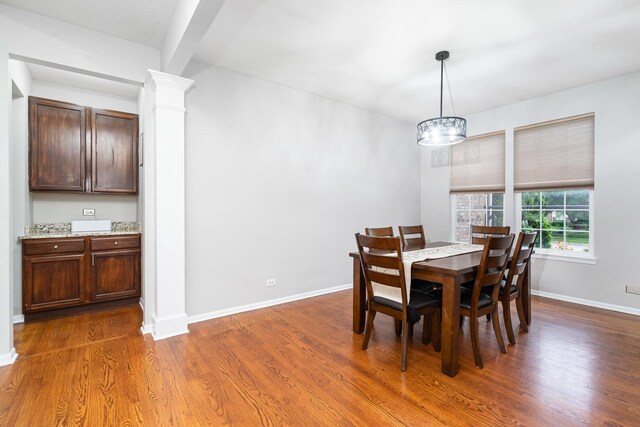 24723 W Champion Dr, Plainfield, IL 60585 - dining area featuring wood finished floors, a chandelier, baseboards, and ornate columns