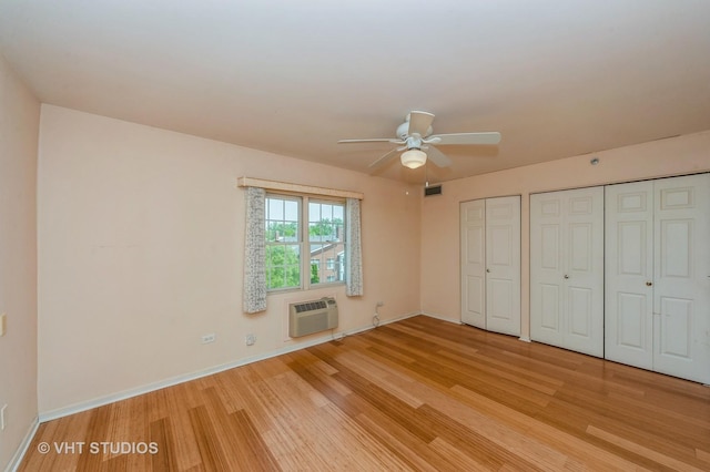 1220 Depot St Unit 411, Glenview, IL 60025 - unfurnished bedroom featuring light wood finished floors, an AC wall unit, multiple closets, baseboards, and ceiling fan