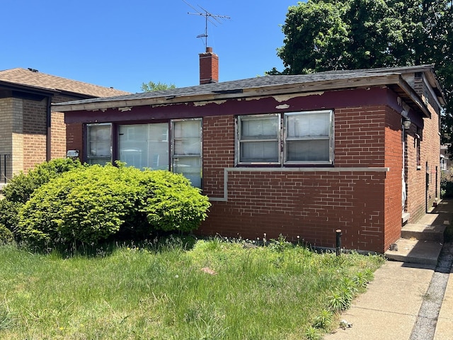 11115 S S Ave L, Chicago, IL 60617 - view of home's exterior featuring brick siding, a chimney, and a shingled roof