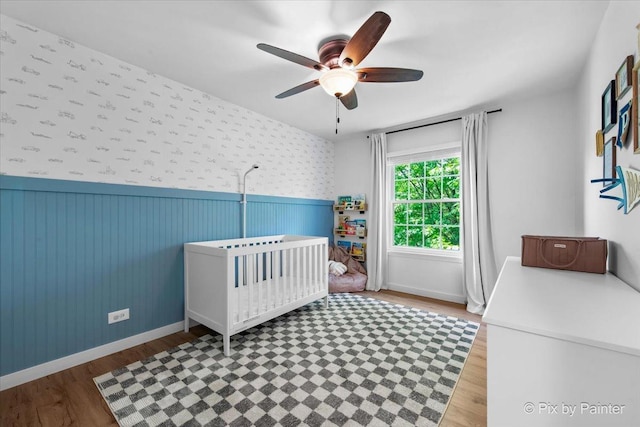 2552 Autumn Grove Ct, Aurora, IL 60504 - bedroom with a wainscoted wall, wood finished floors, a crib, baseboards, and a ceiling fan