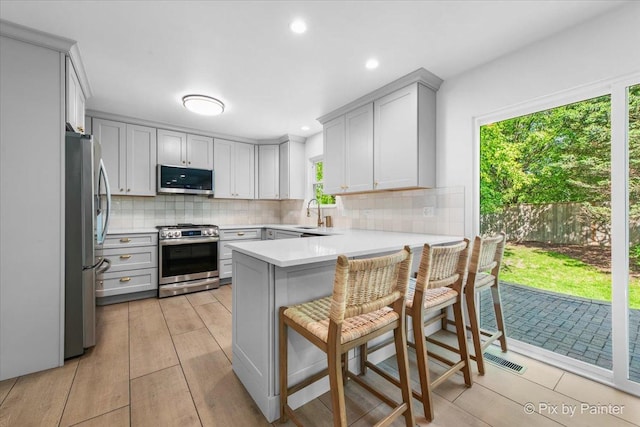 2552 Autumn Grove Ct, Aurora, IL 60504 - kitchen with appliances with stainless steel finishes, a peninsula, gray cabinetry, backsplash, and recessed lighting