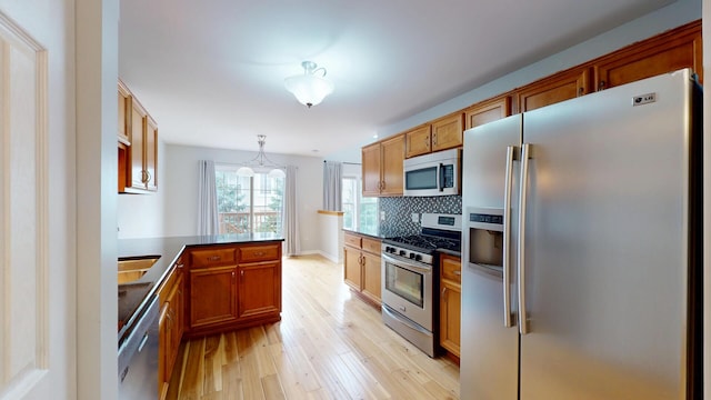 16158 Hillcrest Cir, Orland Park, IL 60467 - kitchen with appliances with stainless steel finishes, light wood finished floors, a peninsula, dark countertops, and tasteful backsplash