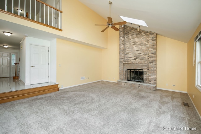 2755 Newport Dr, Naperville, IL 60565 - unfurnished living room featuring high vaulted ceiling, carpet flooring, ceiling fan, a skylight, and a brick fireplace