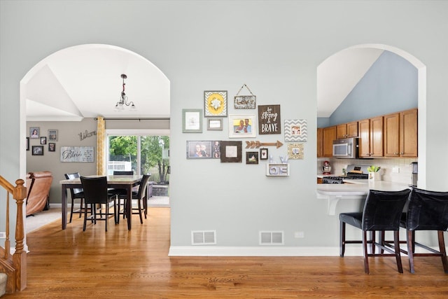 25516 W Gateway Cir, Plainfield, IL 60585 - dining area with vaulted ceiling, light wood-style floors, baseboards, and arched walkways