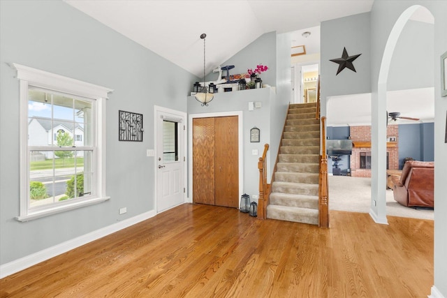 25516 W Gateway Cir, Plainfield, IL 60585 - entrance foyer featuring light wood-style floors, high vaulted ceiling, a fireplace, stairway, and baseboards
