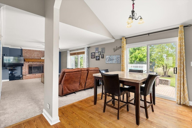 25516 W Gateway Cir, Plainfield, IL 60585 - dining room with light wood-style flooring, a fireplace, a chandelier, lofted ceiling, and ornamental molding
