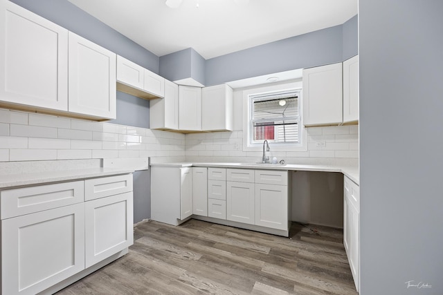 8425 S Essex Ave, Chicago, IL 60617 - kitchen featuring a sink, wood finished floors, backsplash, white cabinets, and light countertops