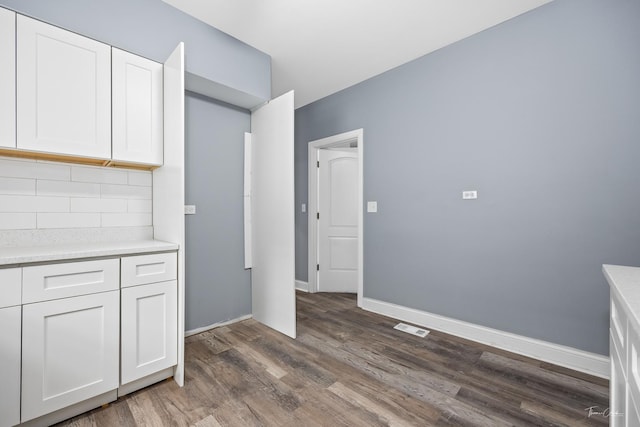 8425 S Essex Ave, Chicago, IL 60617 - kitchen featuring dark wood-style floors, decorative backsplash, light countertops, white cabinetry, and baseboards