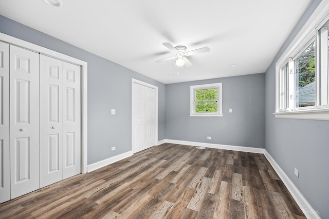8425 S Essex Ave, Chicago, IL 60617 - unfurnished bedroom featuring multiple closets, dark wood-style flooring, baseboards, and a ceiling fan