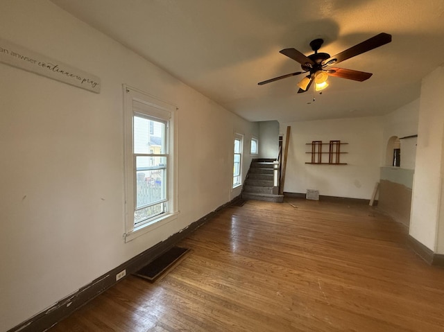 705 Campbell St, Joliet, IL 60435 - unfurnished living room with baseboards, stairway, wood finished floors, a ceiling fan, and arched walkways