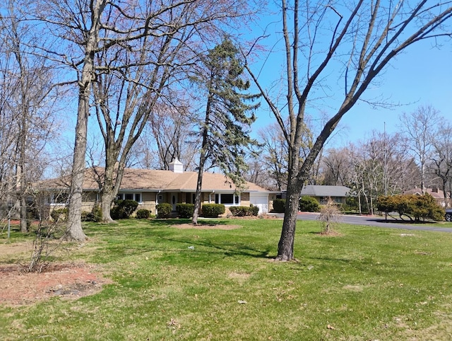 17W120 Woodland Ave, Bensenville, IL 60106 - view of front of property featuring an attached garage, asphalt driveway, a front lawn, and a chimney