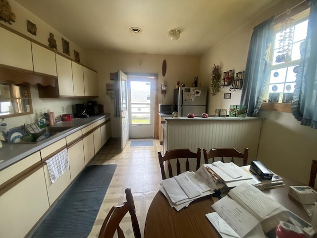 131 S 3rd St, Oregon, IL 61061 - kitchen with freestanding refrigerator, a sink, light floors, and white cabinetry