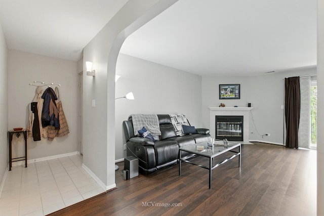 7811 W 157th St Unit 2N, Orland Park, IL 60462 - living room featuring arched walkways, wood finished floors, baseboards, and a fireplace with flush hearth