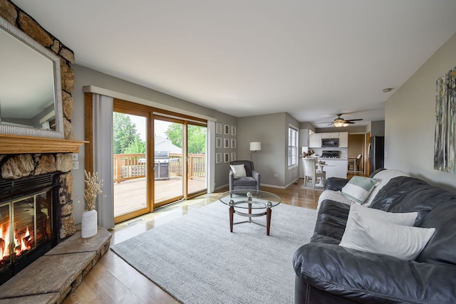 1068 Big Eagle Trl, Carol Stream, IL 60188 - living area featuring a stone fireplace, light wood-type flooring, a ceiling fan, and baseboards