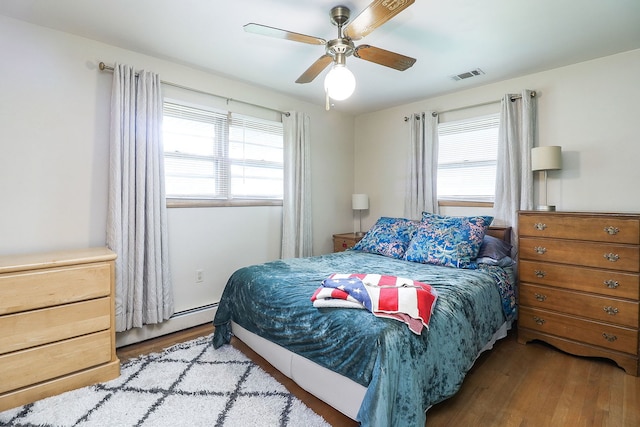 1320 Adeline Ct, Aurora, IL 60505 - bedroom featuring wood finished floors, multiple windows, a baseboard heating unit, and a ceiling fan