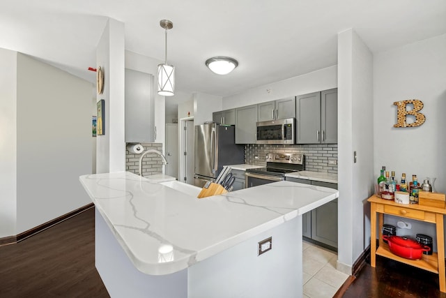 222 N Columbus Dr Unit 2408, Chicago, IL 60601 - kitchen featuring appliances with stainless steel finishes, gray cabinetry, tasteful backsplash, and a peninsula