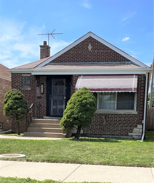 9830 S Ellis Ave, Chicago, IL 60628 - view of front of property featuring brick siding, a chimney, and a front yard