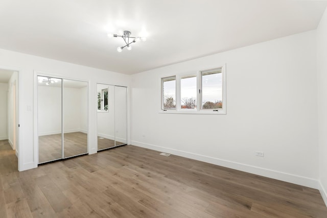 7723 W 157th St, Orland Park, IL 60462 - unfurnished bedroom with two closets, baseboards, and light wood-style flooring
