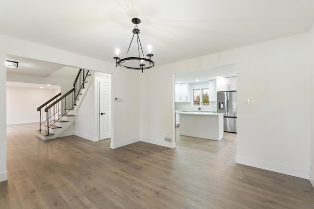 7723 W 157th St, Orland Park, IL 60462 - unfurnished living room featuring stairs, light wood-style floors, a chandelier, and baseboards