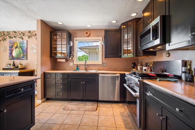 315 S Bone Dr, Normal, IL 61761 - kitchen featuring appliances with stainless steel finishes, light tile patterned flooring, a textured ceiling, glass insert cabinets, and light countertops