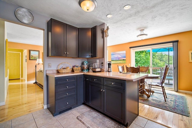 315 S Bone Dr, Normal, IL 61761 - kitchen featuring light countertops, a peninsula, a textured ceiling, and light tile patterned floors