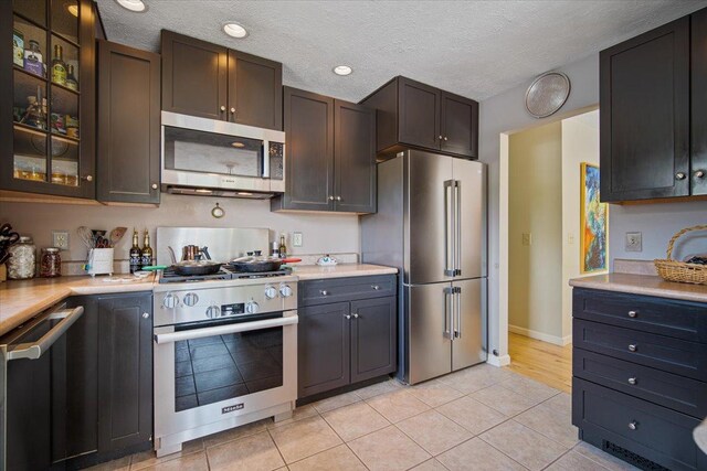 315 S Bone Dr, Normal, IL 61761 - kitchen with stainless steel appliances, light countertops, glass insert cabinets, light tile patterned flooring, and a textured ceiling