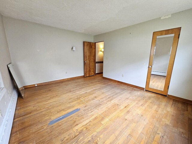 1212 N Mill St, Pontiac, IL 61764 - unfurnished room featuring baseboard heating, wood finished floors, and a textured ceiling