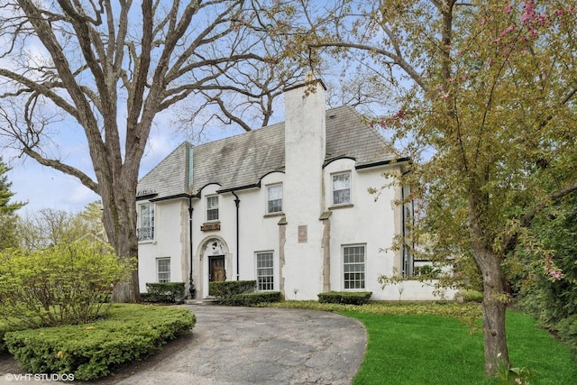 1025 Sheridan Rd, Wilmette, IL 60091 - french country style house featuring stucco siding, a chimney, a front yard, and a high end roof