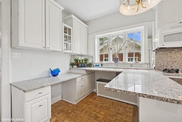1025 Sheridan Rd, Wilmette, IL 60091 - kitchen with white microwave, white cabinetry, decorative backsplash, glass insert cabinets, and light stone counters