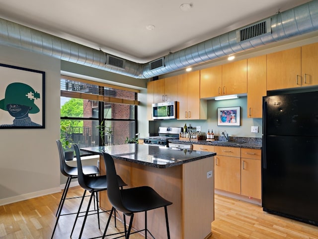 4537 S Drexel Blvd Unit 303, Chicago, IL 60653 - kitchen featuring appliances with stainless steel finishes, a center island, light wood-type flooring, and a kitchen bar