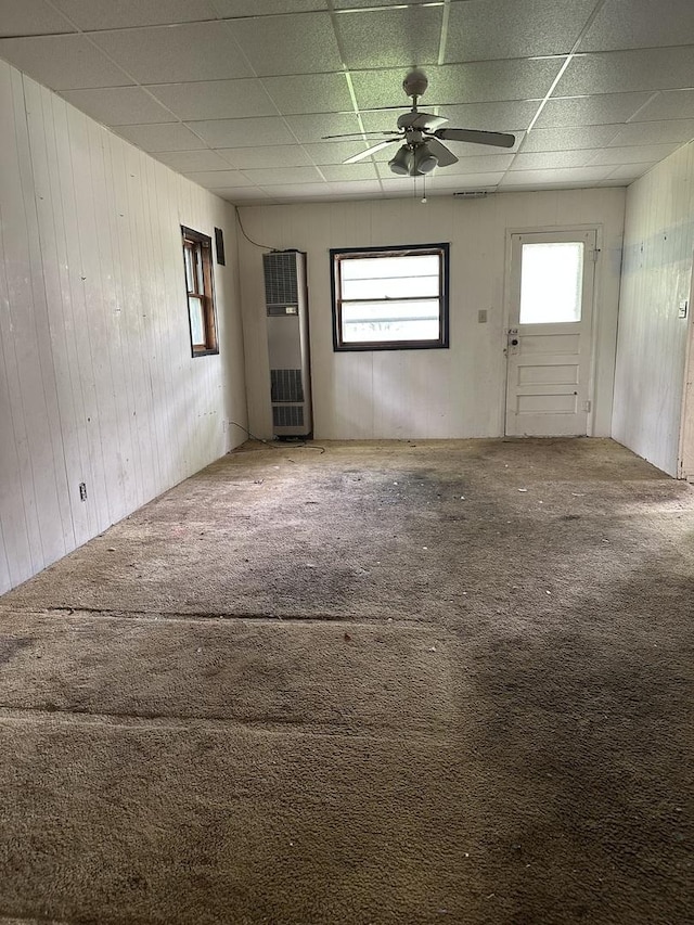 415 W Main St, Arcola, IL 61910 - unfurnished living room with a paneled ceiling, a heating unit, wooden walls, carpet floors, and ceiling fan