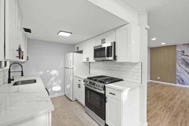 4574 Whitney Dr, Hanover Park, IL 60133 - kitchen with stainless steel appliances, a sink, white cabinetry, baseboards, and light stone counters