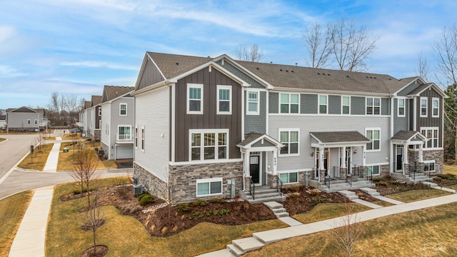 642 Wolverine Dr, Aurora, IL 60502 - townhome / multi-family property featuring stone siding, board and batten siding, a residential view, roof with shingles, and central AC unit