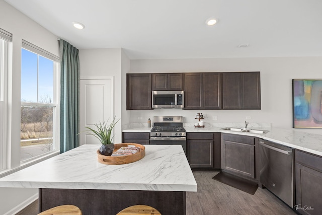 642 Wolverine Dr, Aurora, IL 60502 - kitchen with appliances with stainless steel finishes, a sink, dark brown cabinets, dark wood-style flooring, and a center island