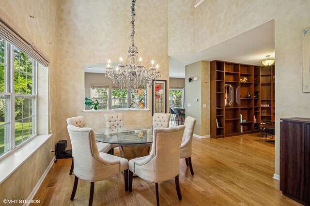 6068 Halloran Ln, Hoffman Estates, IL 60192 - dining room featuring a chandelier, wood finished floors, healthy amount of natural light, a towering ceiling, and baseboards