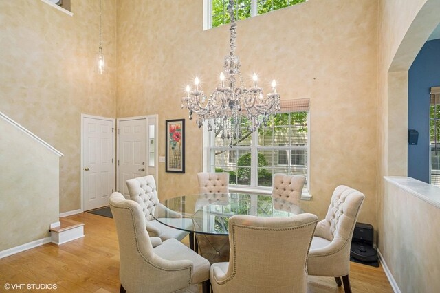 6068 Halloran Ln, Hoffman Estates, IL 60192 - dining area with arched walkways, a high ceiling, wood finished floors, a chandelier, and baseboards