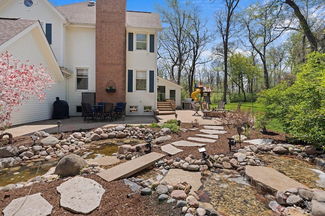 2905 Rose Ave, Mchenry, IL 60050 - rear view of house featuring a patio, a chimney, a shingled roof, and entry steps
