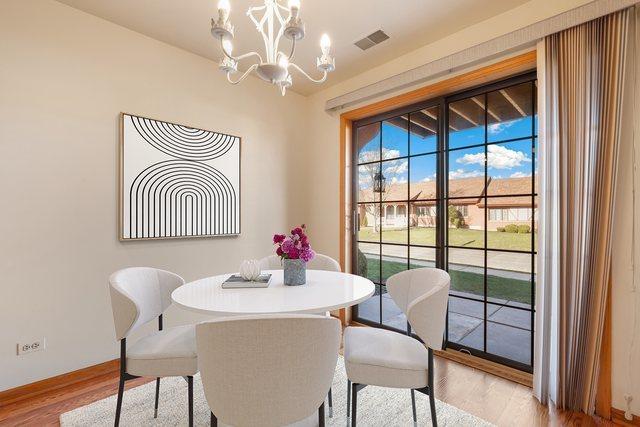 11545 Autobahn Dr E Unit 101, Palos Park, IL 60464 - dining area with light wood finished floors, a chandelier, and baseboards