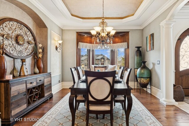 22957 Devonshire Ln, Frankfort, IL 60423 - dining space featuring a chandelier, ornate columns, a tray ceiling, dark wood-type flooring, and crown molding