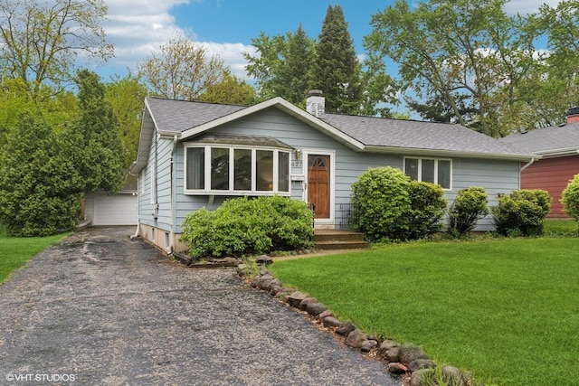 427 Lawrence Ave, Grayslake, IL 60030 - view of front of house featuring a chimney, a front yard, an outdoor structure, a garage, and roof with shingles