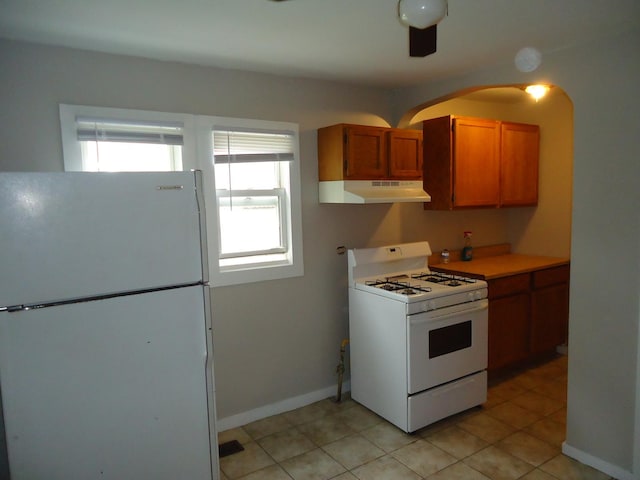 12438 Maple Ave, Blue Island, IL 60406 - kitchen featuring white appliances, under cabinet range hood, brown cabinets, light countertops, and arched walkways