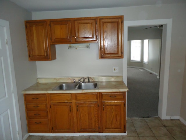 12438 Maple Ave, Blue Island, IL 60406 - kitchen featuring a sink, brown cabinetry, light countertops, baseboards, and light tile patterned floors