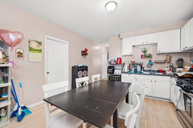 3034 S Komensky Ave, Chicago, IL 60623 - kitchen featuring light wood-type flooring, stainless steel gas range, white cabinets, and dark countertops