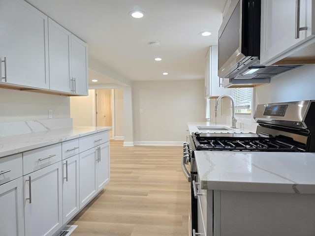 2524 Gray Ct, Waukegan, IL 60085 - kitchen featuring appliances with stainless steel finishes, a sink, baseboards, light wood-style floors, and white cabinetry