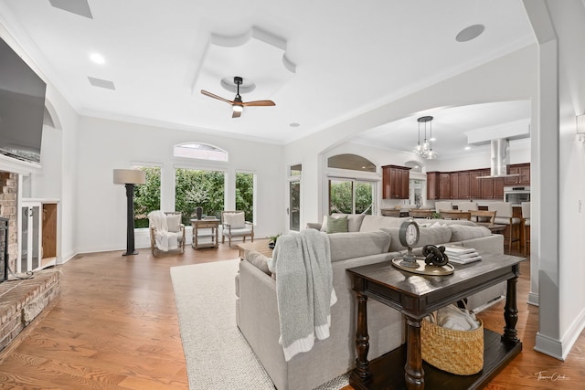 4103 Douglas Rd, Downers Grove, IL 60515 - living room featuring ceiling fan, ornamental molding, arched walkways, light wood-style flooring, and a fireplace with raised hearth