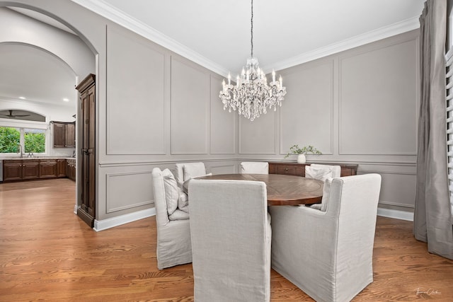 4103 Douglas Rd, Downers Grove, IL 60515 - dining space with a decorative wall, a chandelier, crown molding, light wood finished floors, and arched walkways