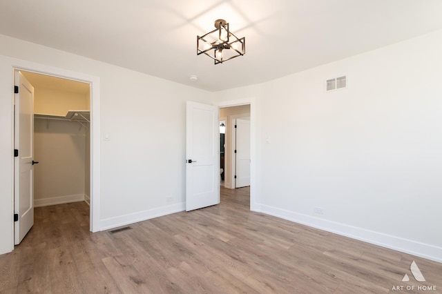 9859 S 81st Ave, Palos Hills, IL 60465 - unfurnished bedroom with a chandelier, light wood finished floors, baseboards, and a spacious closet