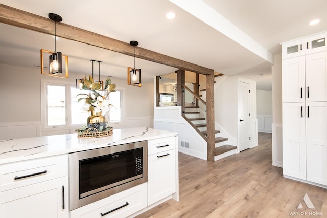 9859 S 81st Ave, Palos Hills, IL 60465 - kitchen featuring built in microwave, light stone countertops, wainscoting, white cabinets, and light wood-style floors