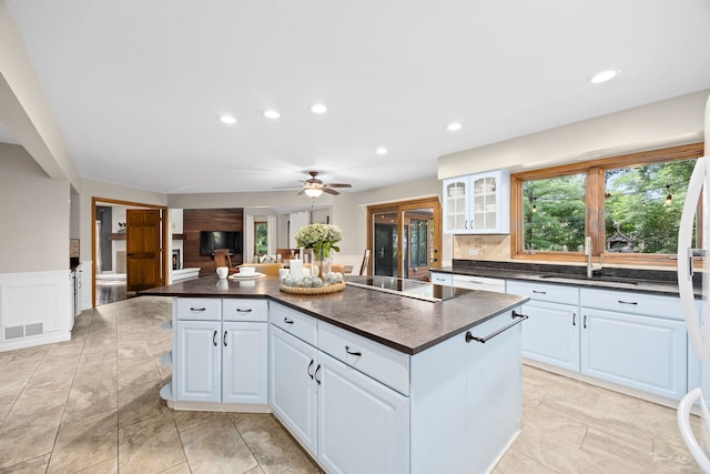 2734 Alyssa Dr, Naperville, IL 60565 - kitchen featuring dark countertops, a kitchen island, black electric stovetop, white cabinets, and wainscoting