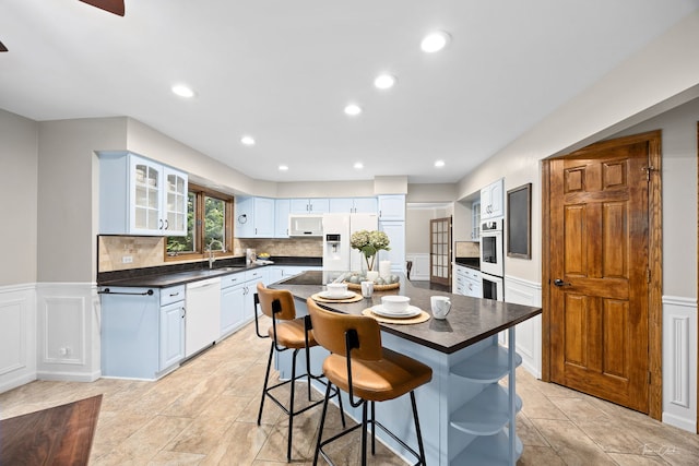 2734 Alyssa Dr, Naperville, IL 60565 - kitchen with white appliances, dark countertops, glass insert cabinets, a kitchen bar, and a wainscoted wall